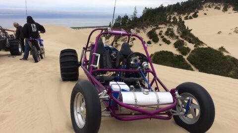 Buggies and dirt bike in sand dunes.